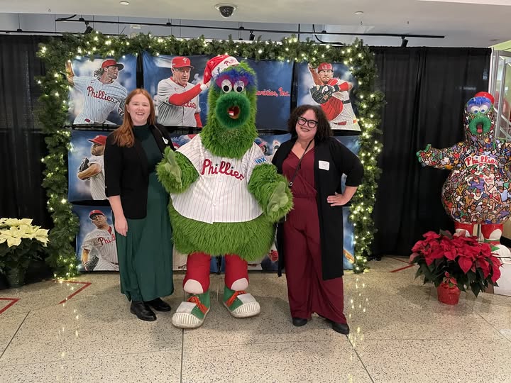 Two Gift of Life Howie's House employees standing next to the Phillies mascot Phillie Phanatic