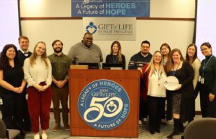 Transplant Information Center Department members and other Gift of Life staff surrounding podium, TIC member holding All-Star plate