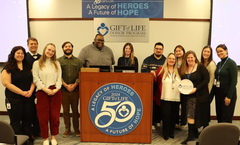 Transplant Information Center Department members  and other Gift of Life staff surrounding podium, TIC member holding All-Star plate