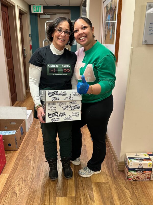 two women smiling, one holding a box