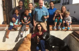 Jim pictured centered surrounded by his wife, children and grandkids and pet dog.