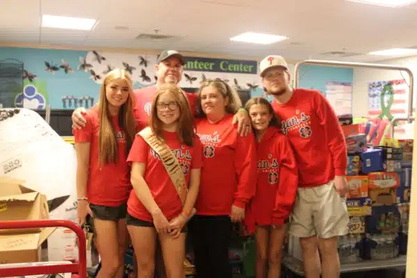 Family of 6 gathered together in the Gift of Life Howie's House Volunteer center surrounded by their recent pantry donations