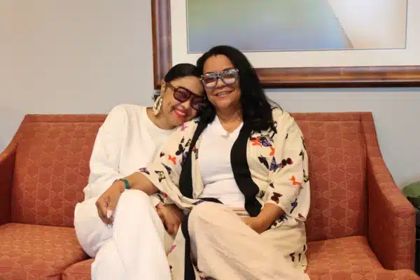 Photo depicts on the left Chelsea a lung transplant recipient smiling and hugging her smiling Mother Nicole, her caregiver. Located in the Gift of Life Howie's House c social work office seated on a sofa.